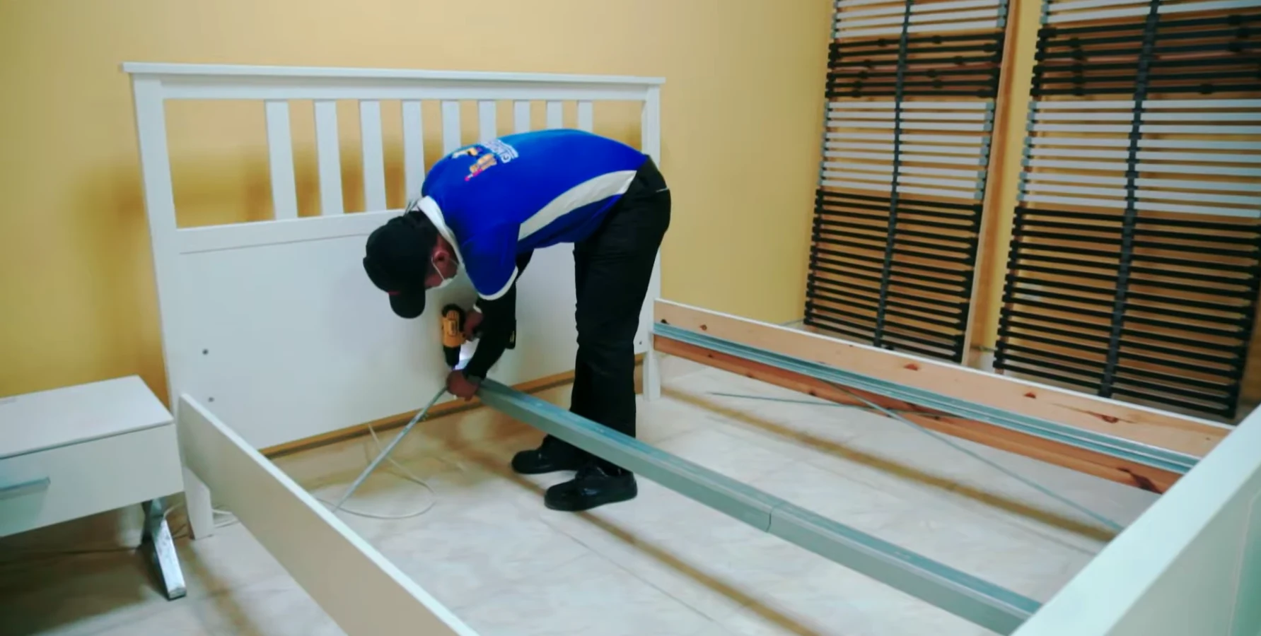 Furniture mover assembling a bed frame with a drill in a Dubai bedroom