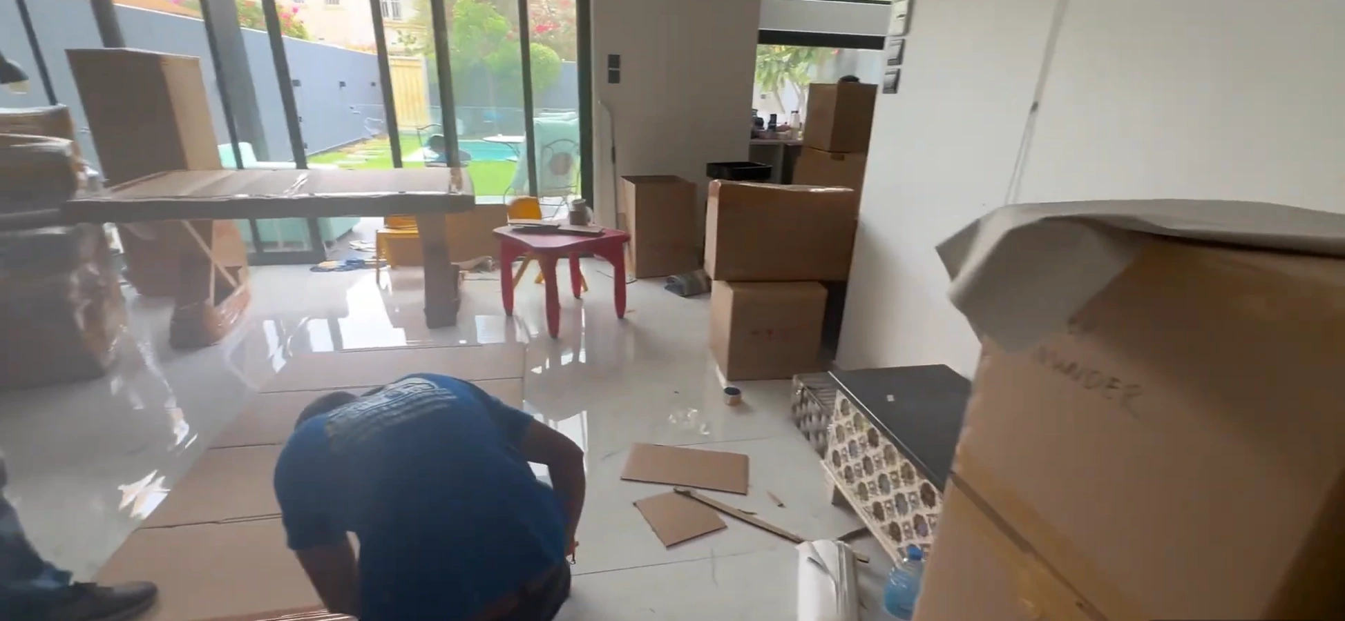 Mover packing boxes inside villa with pool view during villa move in Dubai