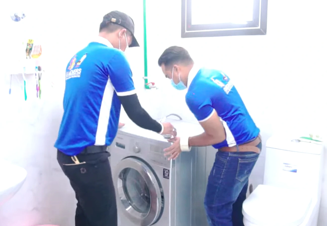 Movers installing a washing machine in bathroom during residential move in Dubai