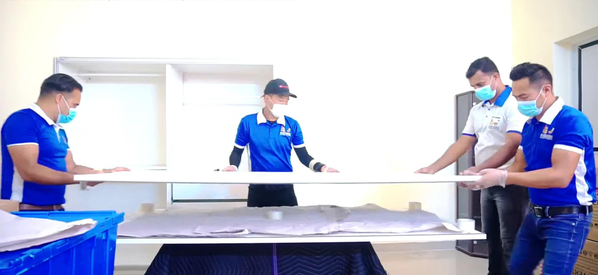 Four movers lifting a large office desk during a commercial relocation in Dubai