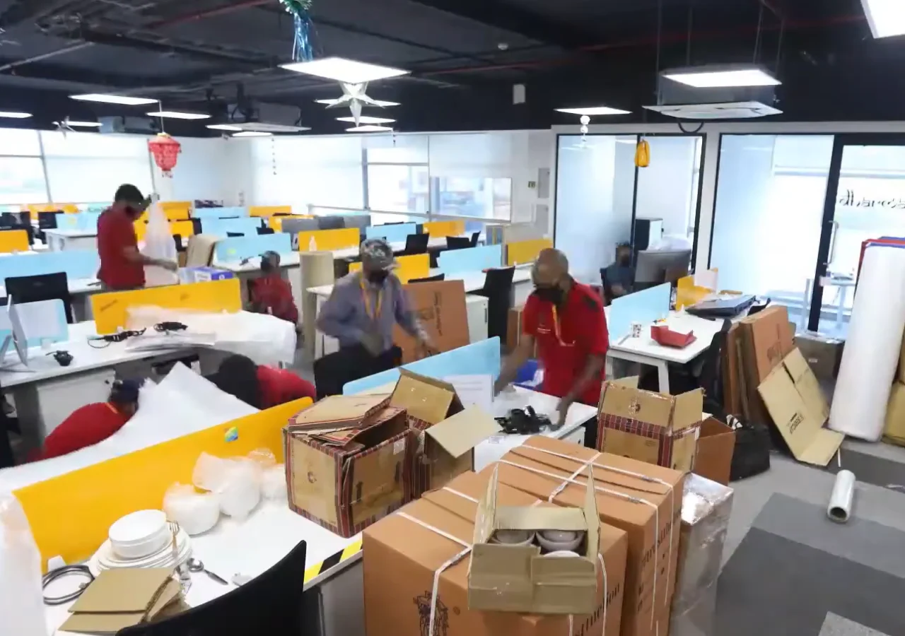 Moving team packing boxes across open office floor during commercial relocation Dubai
